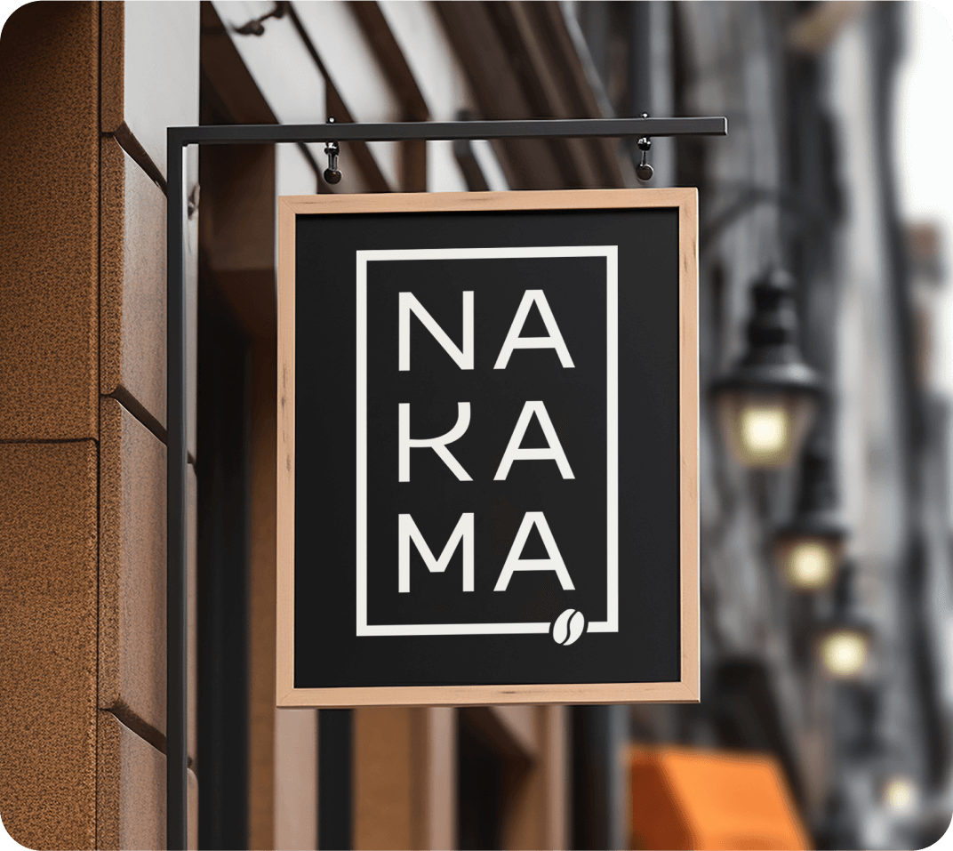 A store sign on a street wall displaying the Nakama Coffee logo.